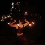 Captivating fire dancer performing during a nighttime show with blazing tools.
