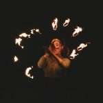 A mesmerizing portrait of a woman performing a fire dance under the night sky.