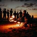 A mesmerizing fire performance on a beach at sunset with a captivated crowd in Goa.